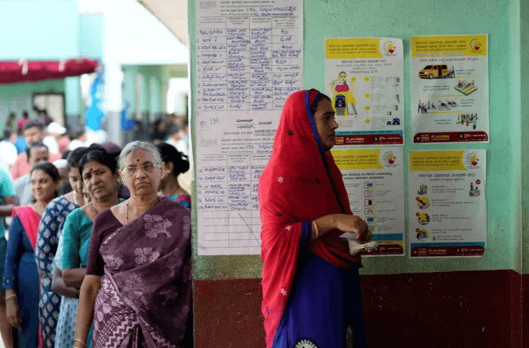 Women wait in a queue to caste their votes at a polling station in Bengaluru [Aijaz Rahi/AP Photo]